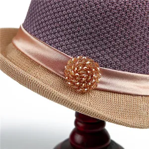 Detail of elegant sun hat with purple straw crown and champagne satin ribbon bead buckle