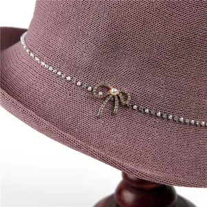 Detail eines lila Flechthutes mit Strassband und Perlenbesatz an der Schleife