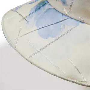 Macro view of floral sun hat featuring silver silk embroidery and breathable cotton texture