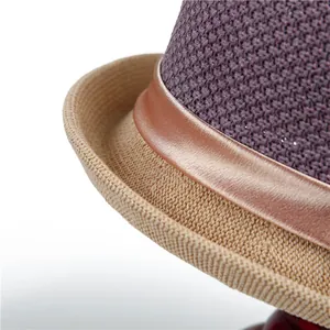 Close-up of textured purple and khaki woven straw hat with brown satin ribbon trim