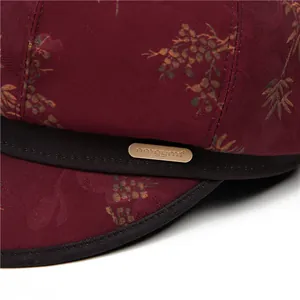 Makro-Detail des weinroten Satinstoffs mit Blumen-Jacquard und goldenem Metalllogo