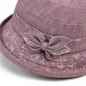 Detail of elegant dusty pink sun hat featuring a layered bow and striped cotton-linen fabric