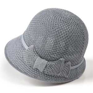 Détail d'un chapeau de soleil en tricot gris clair avec motif au crochet et petit nœud