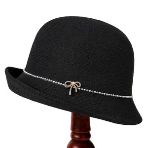 Eleganter schwarzer Strick-Glockenhut mit Strass-Schleife und Perle auf einem Hutständer