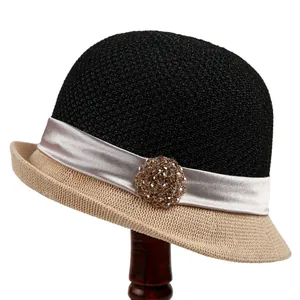 Detail view of woven cloche hat with rhinestone flower decoration and ribbon trim