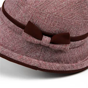 Detailed close-up of woven burgundy fabric and decorative bow on elderly women's sun hat