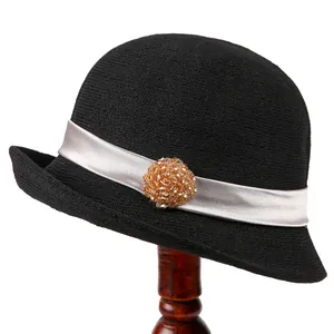 Vintage black knit cloche hat with silver ribbon and amber bead flower on a wood stand