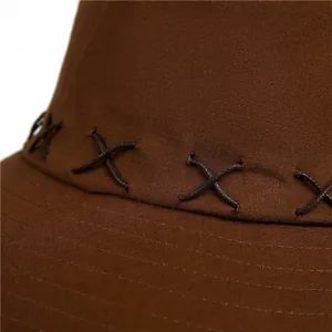 Close-up of deep brown canvas texture and cross-stitch detailing on the wide brim sun hat