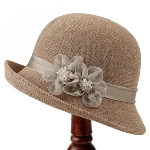 Détail d'un chapeau de paille marron avec ruban de satin et fleurs ornées de perles