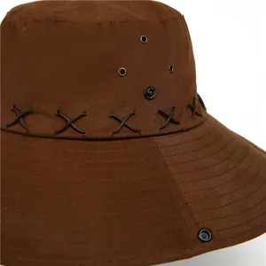 Close-up of brown cowboy hat showing leather cross-stitching and metal ventilation eyelets