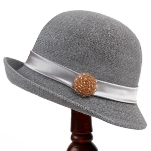 Detailed close-up of grey woven cloche hat with silk ribbon and amber bead ornament