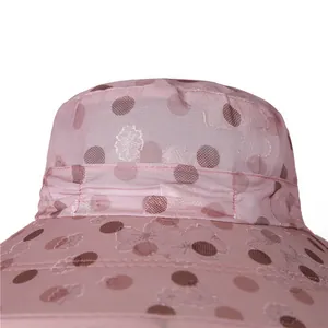 Détail d'un chapeau de soleil rose avec broderie florale et doublure à pois marron