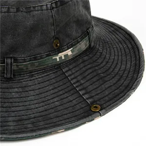 Detail of washed canvas hiking hat with tactical camouflage band and metal buttons