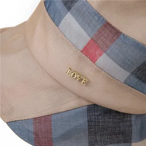 Detail eines Sonnenhutes mit breiter Krempe, Karoband und goldenem LOVE-Anhänger