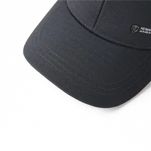 Detalle macro de gorra de béisbol negra con logotipo metálico y textura del tejido