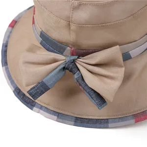 Detailed macro view of khaki sun hat featuring checkered ribbon bow and textured fabric