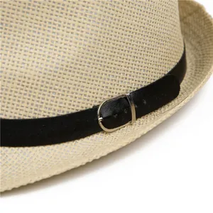 Detalle de sombrero de paja tejido con correa de cuero negro y hebilla de metal plateado