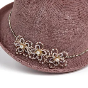 Détail d'un chapeau en paille rose avec fleurs perlées à la main et strass