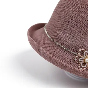 Détail d'une fleur de perles et d'un ruban strass sur un chapeau de soleil tressé rose