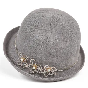 Détail d'un chapeau de paille gris avec fleurs perlées et ornements en strass
