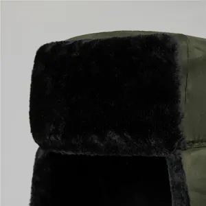 Close-up of thick black faux fur lining and windproof olive green fabric of winter hat