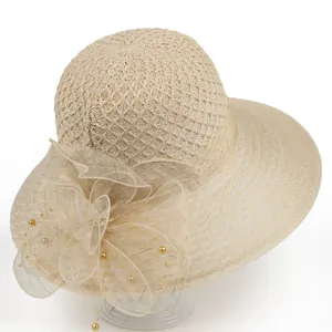Detail of cross-woven wide brim straw hat with elegant mesh flower and pearl accents