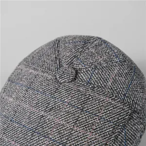 Close-up of winter newsboy hat featuring grey tweed wool texture and top button detail