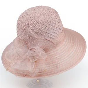 Close-up of pink mesh sun hat featuring a large gauze bow and faux pearl details