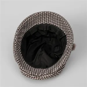 Détail d'un chapeau cloche en laine montrant la doublure noire et le pompon brun