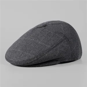 Detailed close-up of dark grey knitted texture and top button on a winter flat cap