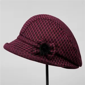 Détail d'un chapeau en laine à carreaux rouge et noir avec nœud et pompon en fourrure