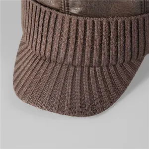 Close-up of deep brown leather stitching and thick ribbed knit texture on a winter hat
