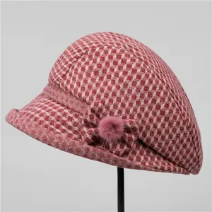 Détail d'un chapeau cloche en laine à carreaux rouges avec nœud et pompon rose pelucheux