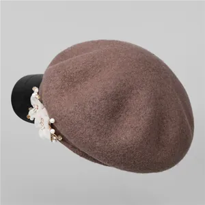 Detail view of brown wool beret with white floral pearl trim and black leather brim