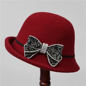 Detail of burgundy wool cloche hat with a large rhinestone-studded bow decoration