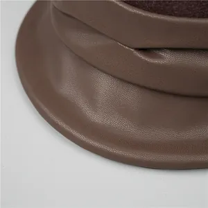 Macro shot of dark brown leather bucket hat showing fine grain texture and neat stitching