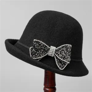 Detailed view of black wool cloche hat featuring a sparkling rhinestone bow decoration