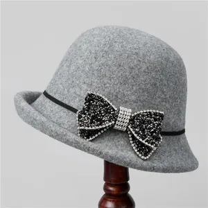 Detail of grey wool fedora featuring a rhinestone bow and black ribbon trim