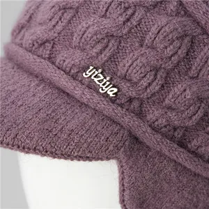 Detail of purple knitted winter hat featuring thick cable knit texture and crystal logo