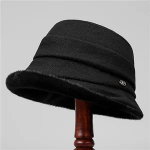 Close-up of black wool cloche hat showing plush faux fur trim and silver logo buckle