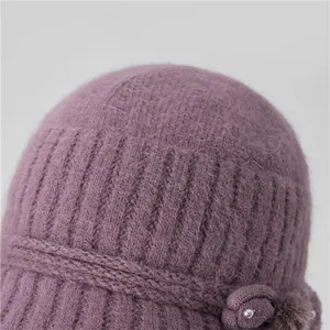 Detail of purple knitted hat featuring floral applique, pearls, and soft faux fur texture