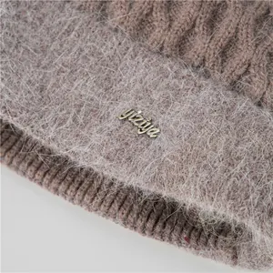 Primer plano del tejido de mohair marrón y la etiqueta metálica dorada en el gorro de invierno