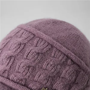 Close-up of purple knitted winter hat showing fuzzy texture and metal letter detail