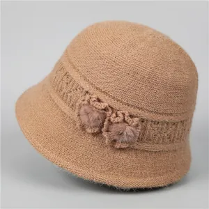 Close-up of a camel knitted cloche hat with floral accents and soft fur pompoms