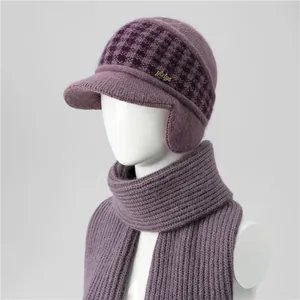Close-up of purple knit hat with ear flaps, houndstooth pattern and gold logo detail