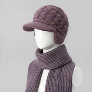 Detail of burgundy knitted hat and scarf set with thick cable pattern and metal logo