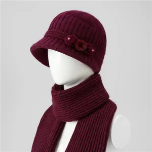 Detail of dark red knitted winter hat and scarf set with fur pom-poms and pearls