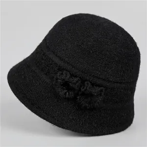 Detail of black knit bucket hat for elderly women with plush fur pompom accents