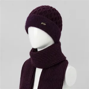 Detalle macro de gorro de punto violeta oscuro y bufanda con logotipo metálico