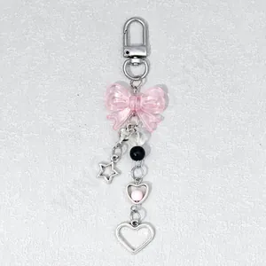 Detail view of pink acrylic bow keychain with silver star and heart charms for phone case